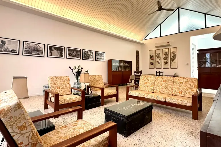 The double-height hall with its teak suite and photograph wall.
