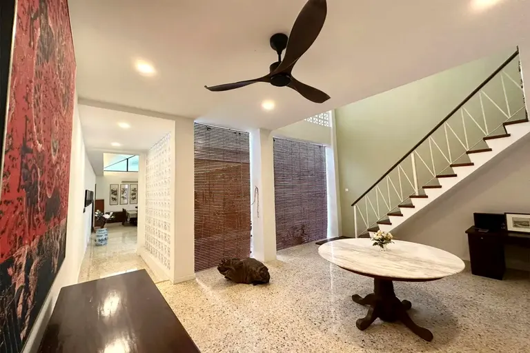 The entry hall and original stair rising along the olive wall.